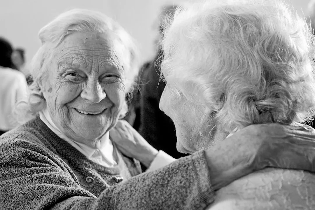 grayscale photo of older woman in sweater smiling